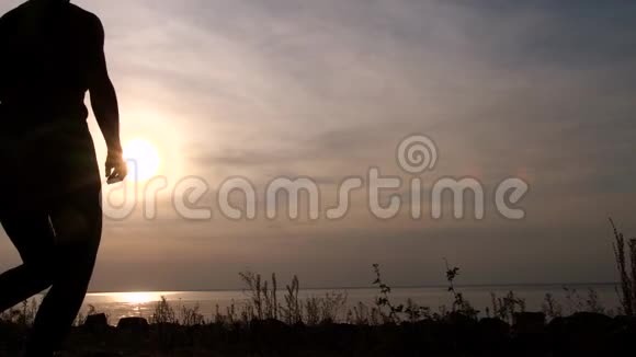 健康的女人在海边享受日落的剪影视频的预览图
