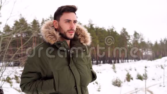 迷人的留着胡子的人站在冬季森林的户外视频的预览图