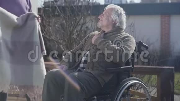 年轻的不可辨认的女性无效的嫩覆盖瘫痪的腿的老白种人男子毛毯快乐男退休视频的预览图