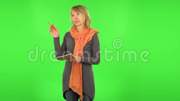 中年金发女人正在思考然后用铅笔在笔记本上写作绿色屏幕视频的预览图