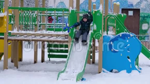 男孩在孩子身上玩冬天在操场上滑滑梯很高兴第一次下雪视频的预览图