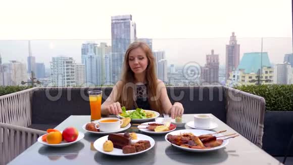 一位年轻女士傍晚独自在一家现代化的城市屋顶餐厅用餐视频的预览图