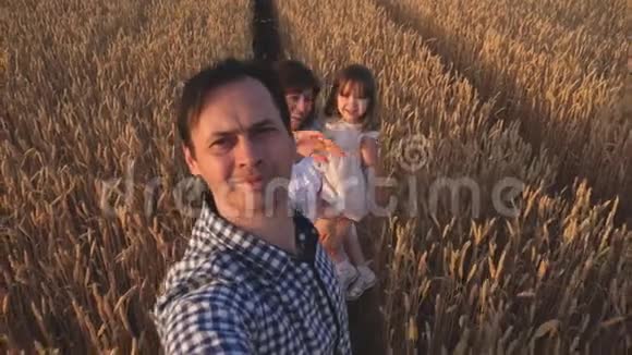 快乐的年轻家庭带着孩子在夏天的田野上散步健康的母亲父亲和小女儿享受大自然视频的预览图