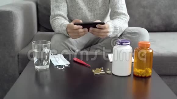 在家里生病时一个年轻人在智能手机上玩电脑游戏视频的预览图