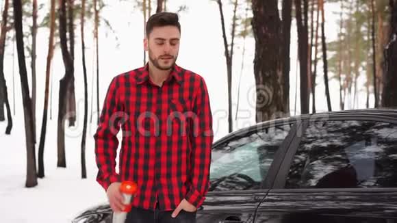 迷人的白种人站在他的车附近的冬季森林里视频的预览图