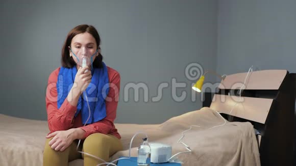 女孩用雾化器使自己吸入一个穿着衣服的年轻女子独自坐在房间里戴着呼吸面罩视频的预览图