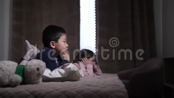 可爱的中国同胞躺在床上看电视视频的预览图