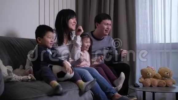 激动人心的亚洲家庭在电视上看足球赛视频的预览图