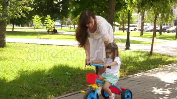 孩子学会骑自行车幸福家庭和童年的概念父母和小女儿在公园散步快乐视频的预览图