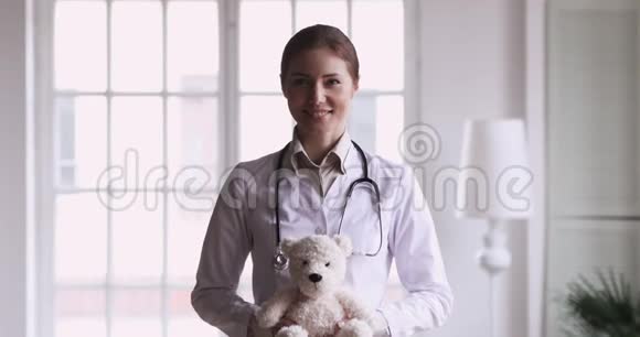 快乐女医生儿科医生抱着泰迪熊看镜头视频的预览图