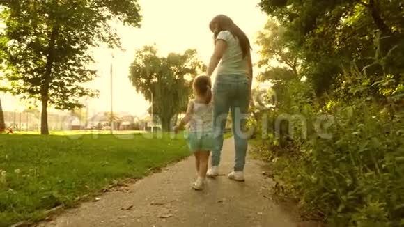 小女儿和妈妈牵着手走着小路宝贝牵着妈妈手妈妈和宝宝在公园休息a的概念视频的预览图