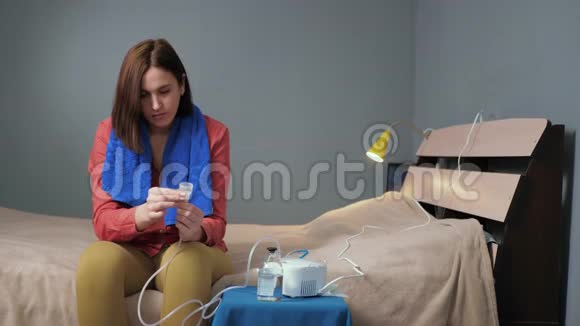 女孩倒盐水吸入雾化器穿着红色衬衫和蓝色毛巾的年轻女子独自坐着视频的预览图