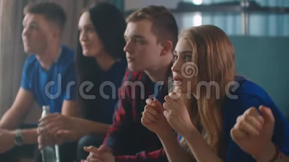 五位年轻的成人朋友在电视上观看体育节目庆祝视频的预览图