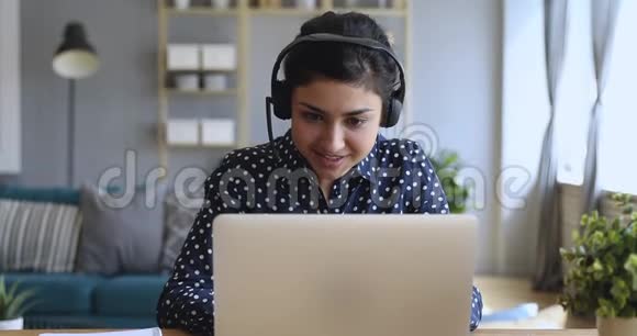 微笑的印度妇女戴着无线耳机视频通话笔记本电脑视频的预览图