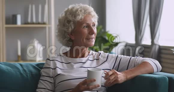 微笑着梦幻般的中年妇女端着一杯热咖啡视频的预览图