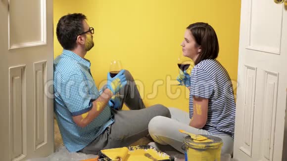 疲惫的一对男女坐在地板上看着油漆过的黄墙喝着酒他们累了但却累了视频的预览图