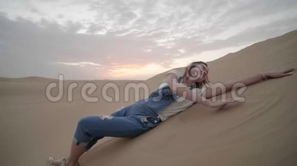 阿联酋沙漠中的幸福女孩躺在沙滩上视频的预览图