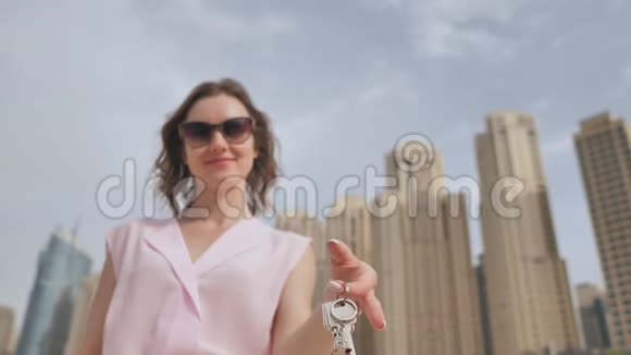 在大城市的摩天大楼里买公寓的概念女孩拿着新家的钥匙视频的预览图