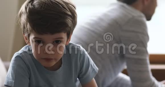 悲伤的小男孩和愤怒的爸爸分别坐在沙发上视频的预览图