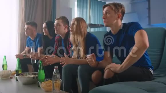 五个朋友坐在家里看电视上的比赛有感情地庆祝赢得胜利的喜悦视频的预览图