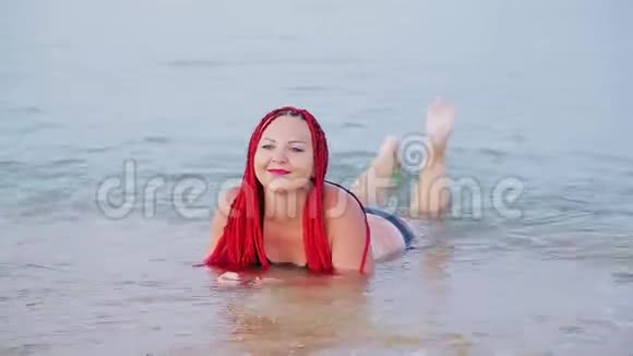 一个年轻的犹太人在度假时扎着红色的辫子躺在海边视频的预览图