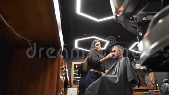 理发店的女理发师用理发刀给留胡子的男人理发男士发式及沙龙理发梳毛视频的预览图