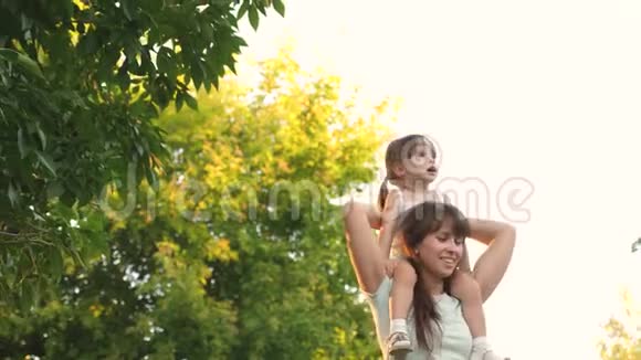 快乐的童年概念母亲扛着她心爱的孩子在公园里妈妈和女儿一起走视频的预览图