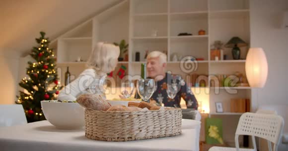 爷爷奶奶坐在圣诞餐桌上吃晚餐安慰家谱视频的预览图