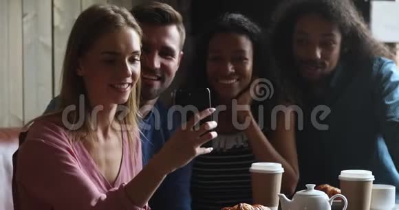 一位高加索人微笑着拿着手机和朋友们自拍视频的预览图
