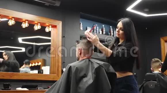 漂亮的理发师女孩用剪刀和梳子剪男人的头发女性理发师为客户服务时髦男人视频的预览图