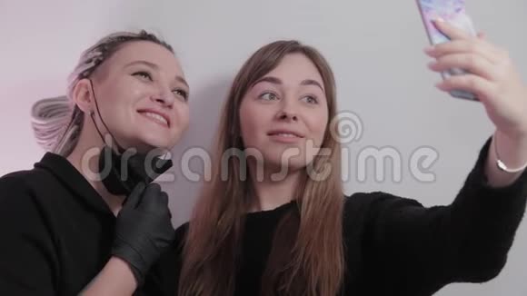 女人化妆师和客户女孩在美容店自拍后的程序视频的预览图