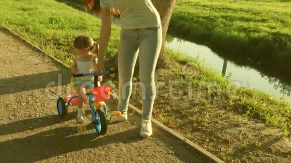 妈妈教女儿在公园里骑自行车妈妈和她的小女儿玩幸福童年的概念视频的预览图