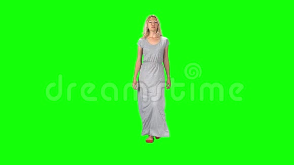 金发女孩穿着一件灰色的长裙对着绿色的屏幕直视着相机慢动作视频的预览图