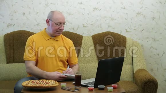 一个拿着笔记本电脑的人正在吃披萨晚餐前完成工作视频的预览图