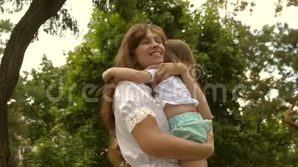 快乐的妈妈在户外的公园里拥抱小女儿漂亮的妈妈和她的孩子正在公园里玩宝贝和拥抱视频的预览图