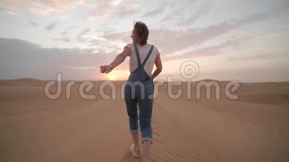 阿拉伯酋长国沙漠中一个快乐的女孩晚上沿着沙丘奔跑视频的预览图