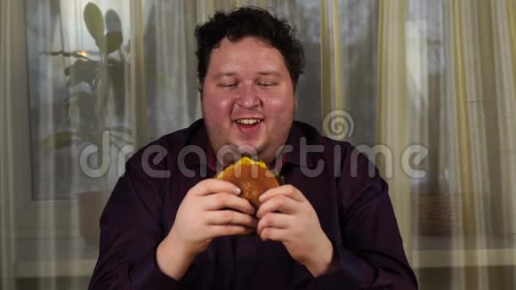 年轻人拿着汉堡包胖子吃快餐汉堡不是有用的食物很饿的家伙视频的预览图