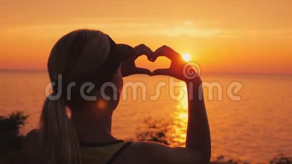 一个女人望着夕阳下的大海露出一个心形的身影视频的预览图