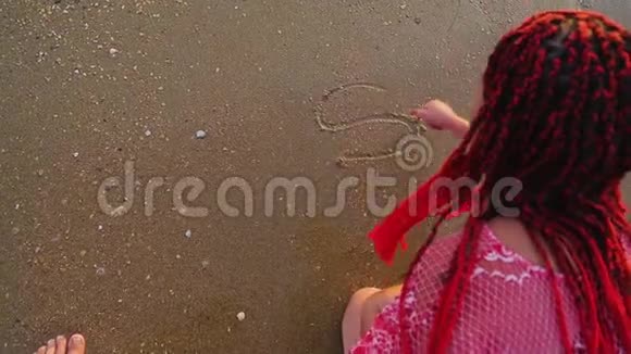 一个女人在沙子里写着共波这个词正在冲走视频的预览图