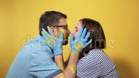 男人和女人在画墙的尽头亲吻快乐它们都被黄色的油漆弄脏了油漆修理工作视频的预览图