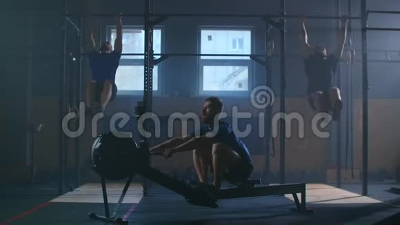 三个人在一个健身室里一起工作一个人拉一台划船机两个人在酒吧里表演拉UPS交叉交叉交叉视频的预览图