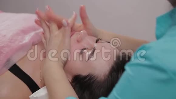 女性按摩师对按摩室的客户进行面部按摩视频的预览图