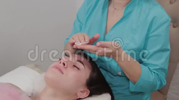女性按摩师对按摩室的客户进行面部按摩视频的预览图