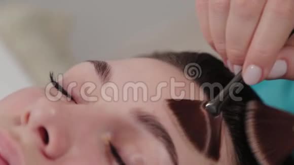 女性按摩治疗师为客户做面部刷按摩视频的预览图
