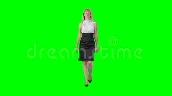 穿着黑白色连衣裙和高跟鞋的金发女孩在绿色屏幕上直视着相机视频的预览图