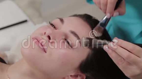 女性按摩治疗师为客户做面部刷按摩视频的预览图