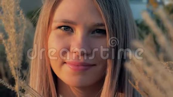 田野里有花的美丽年轻女子的肖像黄金时间视频的预览图