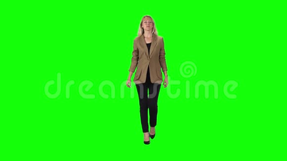 一个金发女孩穿着时髦的棕色夹克黑色裤子和高跟鞋与绿色的屏幕对着慢动作视频的预览图