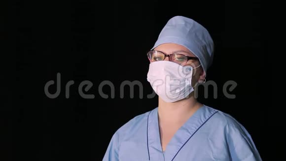 戴着医用口罩的女医生手里拿着一个黑色背景的注射器视频的预览图