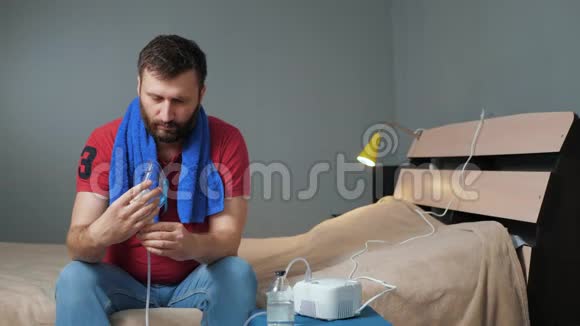 人戴上吸入面罩开启雾化器年轻人一个人坐在房间里戴上口罩吸入视频的预览图